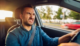 An angry looking man driving a car